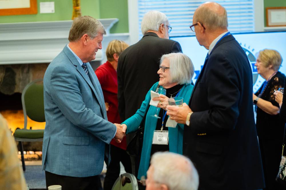 An alumna shakes hands with president T-Haas at the Reunion Dinner.
